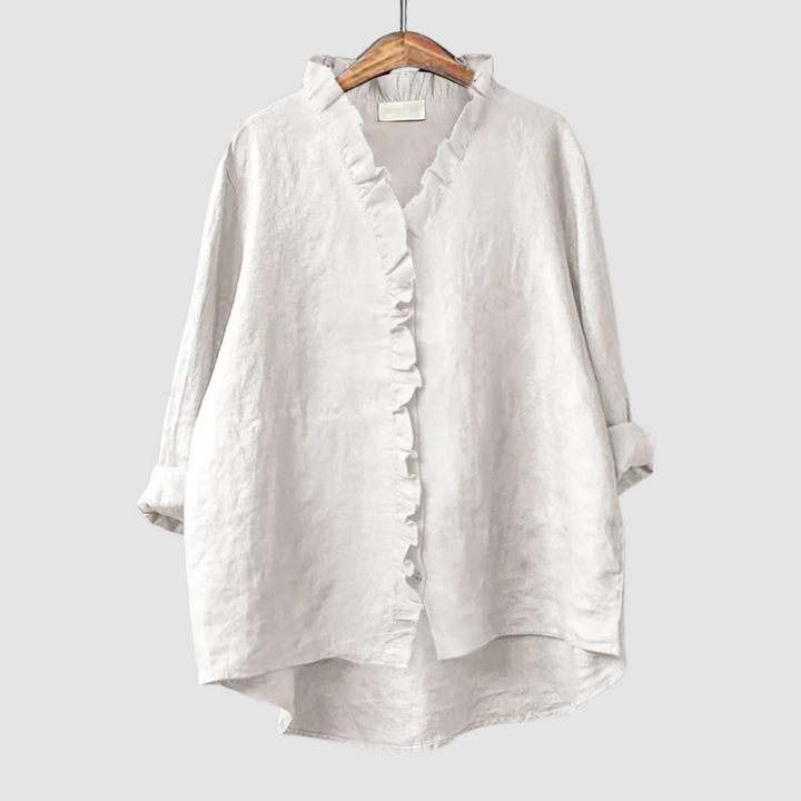 Light white blouse with ruffled collar and button closure on wooden hanger, set against a light gray background.