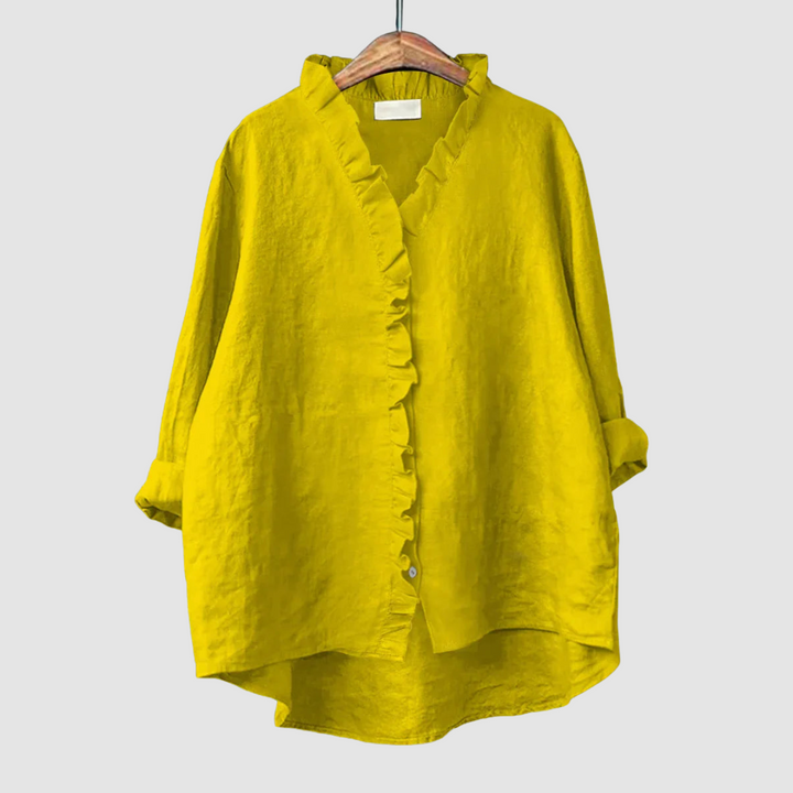 Vibrant yellow blouse with ruffled collar and button closure on wooden hanger, set against a light gray background.