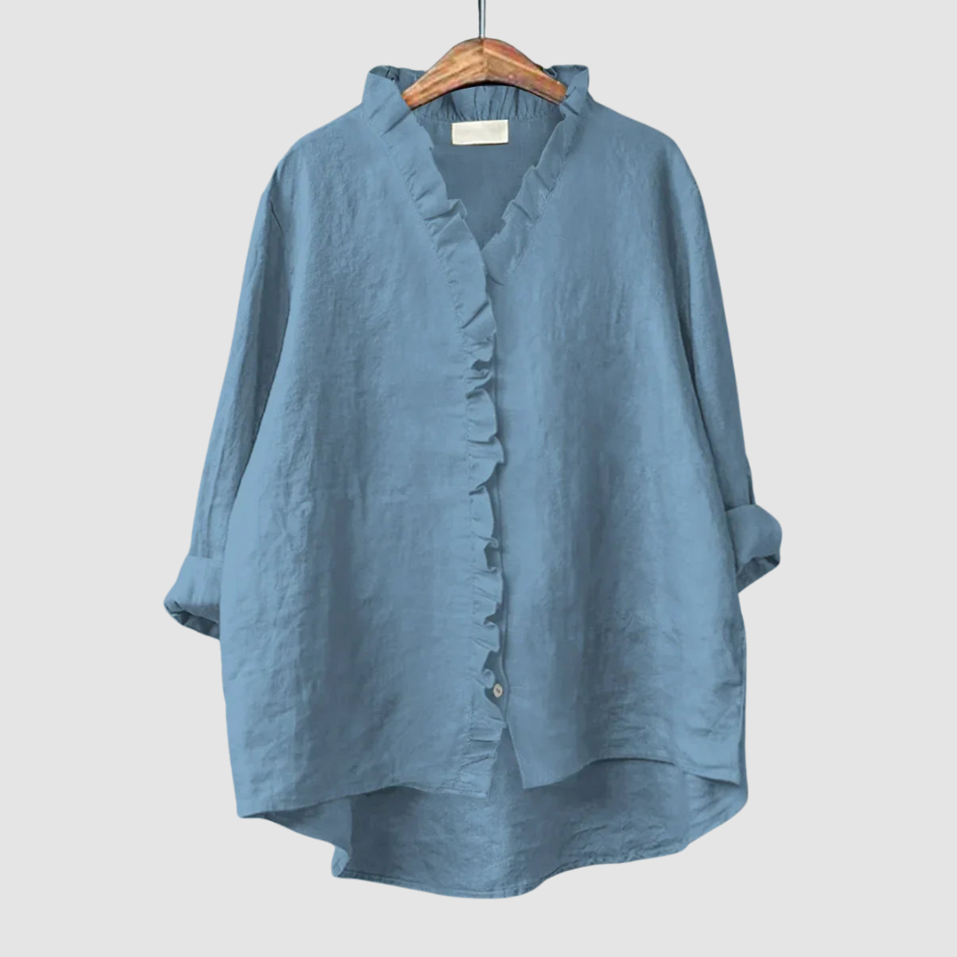 Soft blue blouse with ruffled collar and button closure on wooden hanger, set against a light gray background.