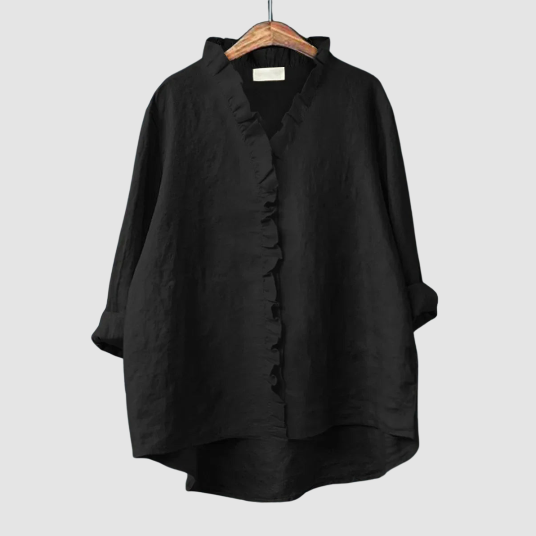 Classic black blouse with ruffled collar and button closure on wooden hanger, set against a light gray background.