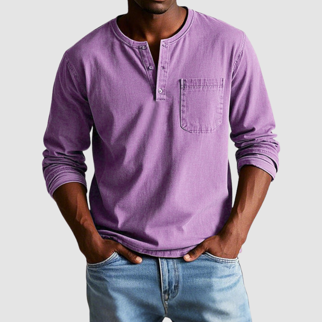Man wearing a purple vintage Henley shirt, hands in pockets, in a studio setting against a light background.