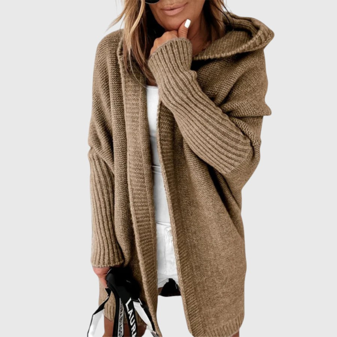 Brown cozy hooded cardigan worn by a person holding a bag, set against a plain background.