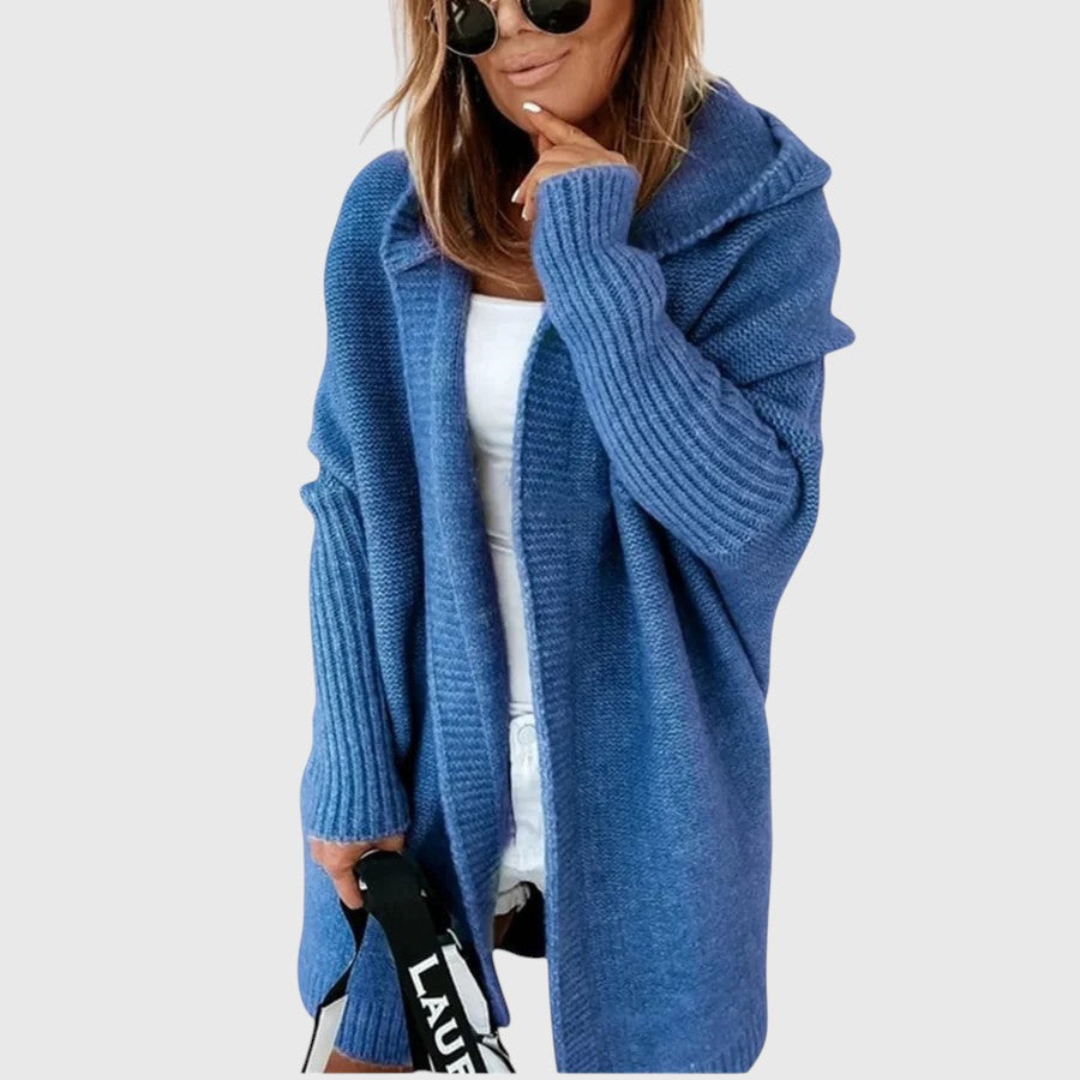 Blue cozy hooded cardigan worn by a person with sunglasses, set against a plain background.