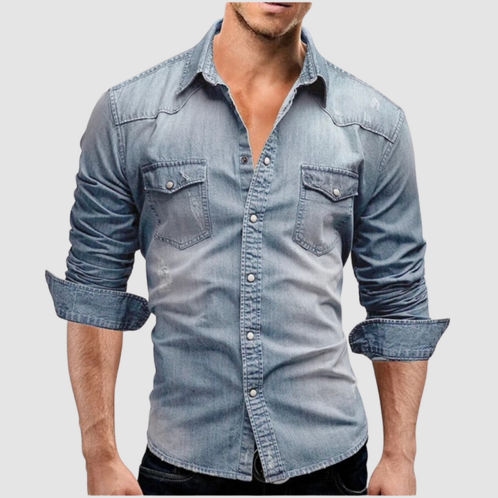 Light blue denim shirt worn by a model, with folded sleeves and button-up front in a studio setting.