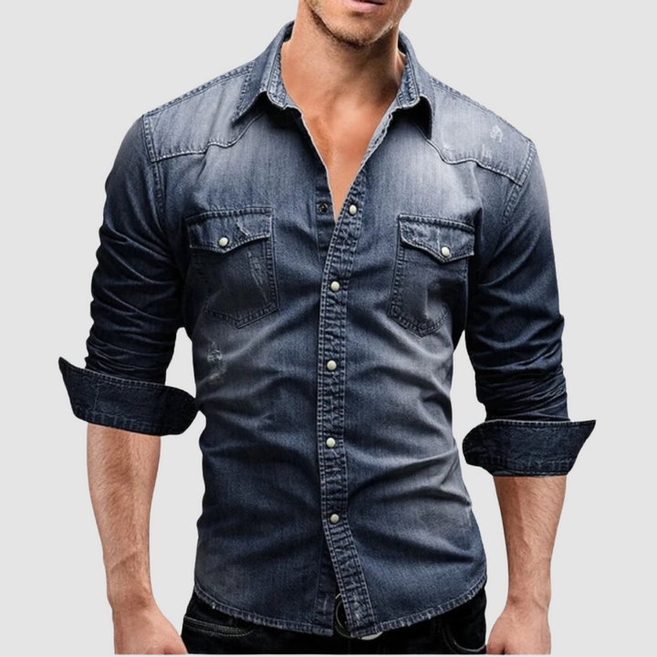 Dark blue denim shirt worn by a model, with folded sleeves and button-up front in a studio setting.