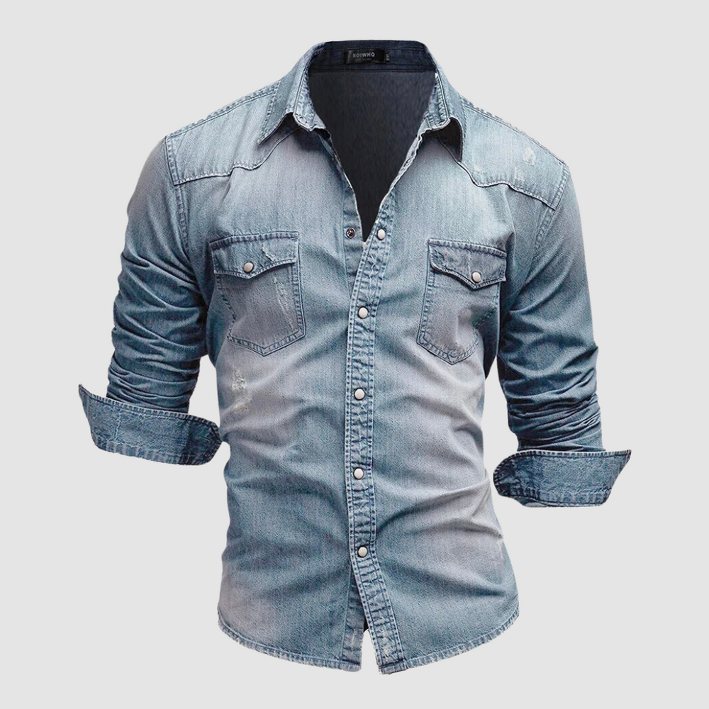 Light blue denim shirt with folded sleeves and button-up front displayed in a studio on a white background.