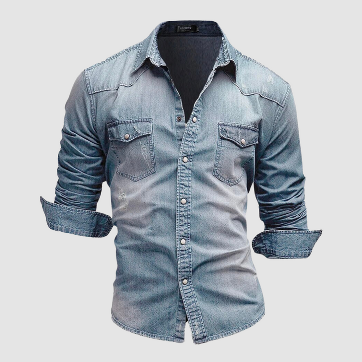 Light blue denim shirt with folded sleeves and button-up front displayed in a studio on a white background.