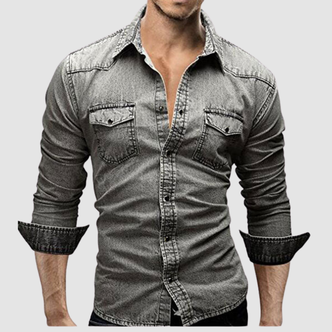 Grey denim shirt worn by a model, with folded sleeves and button-up front in a studio setting.