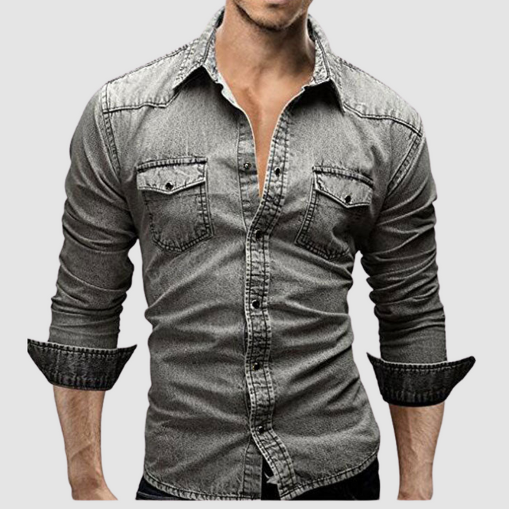 Grey denim shirt worn by a model, with folded sleeves and button-up front in a studio setting.