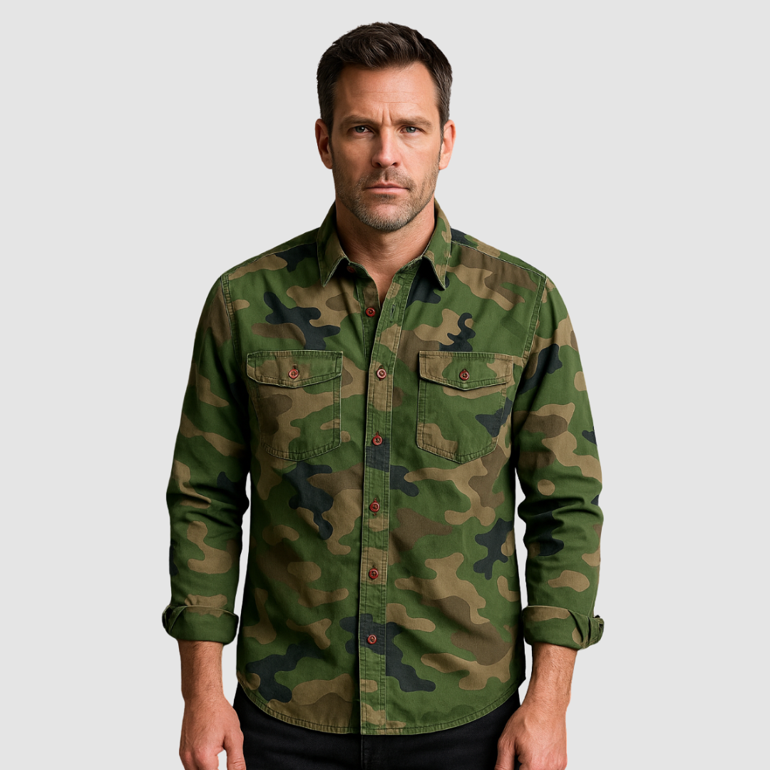 Man wearing a green urban camo shirt with rolled-up sleeves against a plain gray background.
