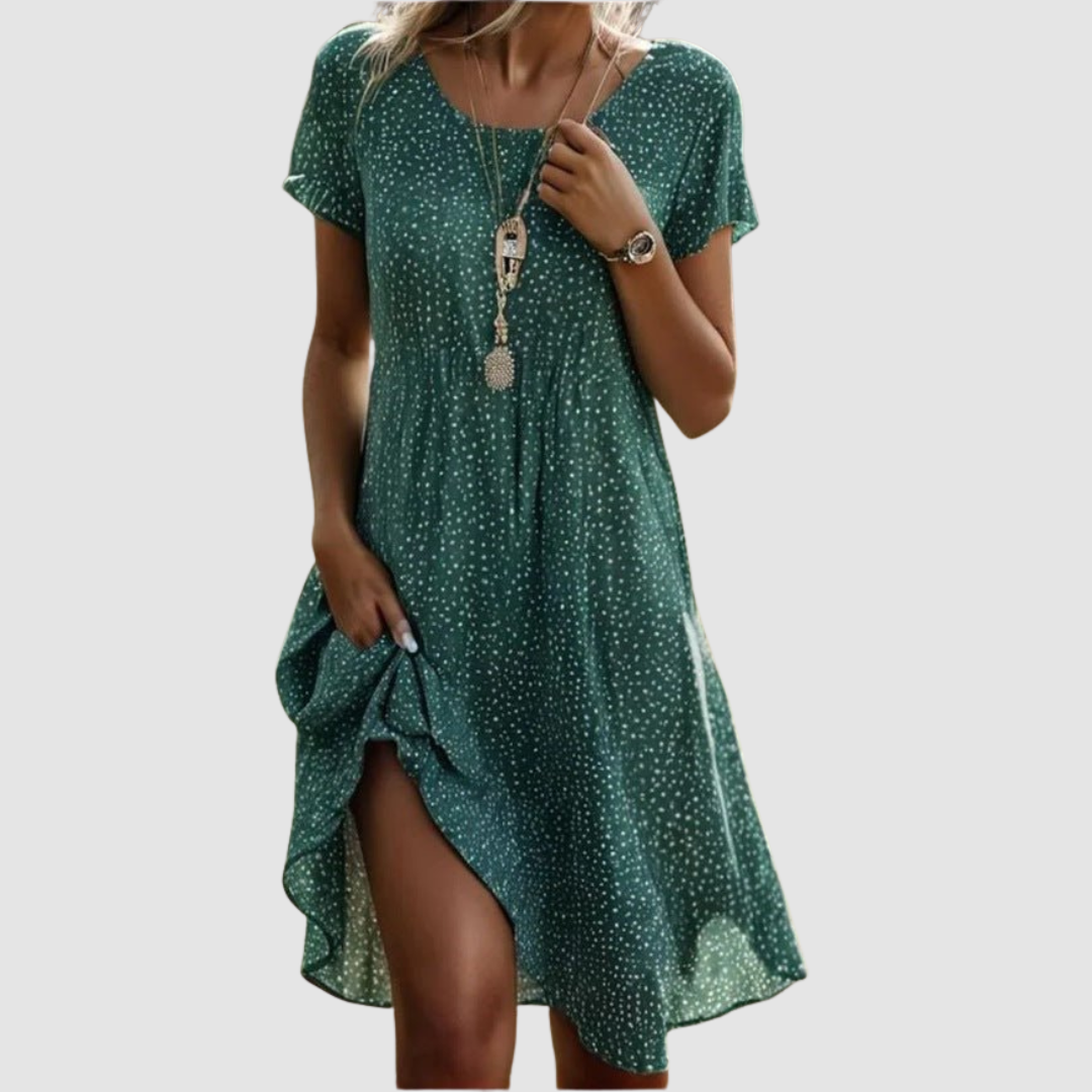Green floral summer dress with a flowing design and short sleeves, modeled in a studio setting.