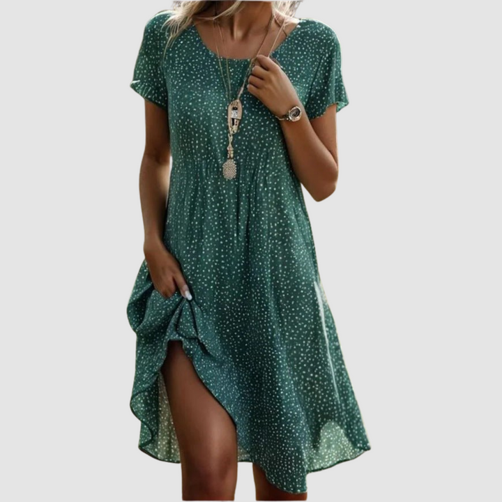 Green floral summer dress with a flowing design and short sleeves, modeled in a studio setting.