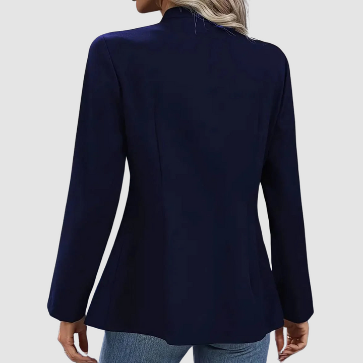 Back view of navy blazer with long sleeves, shown in a casual studio environment with jeans.