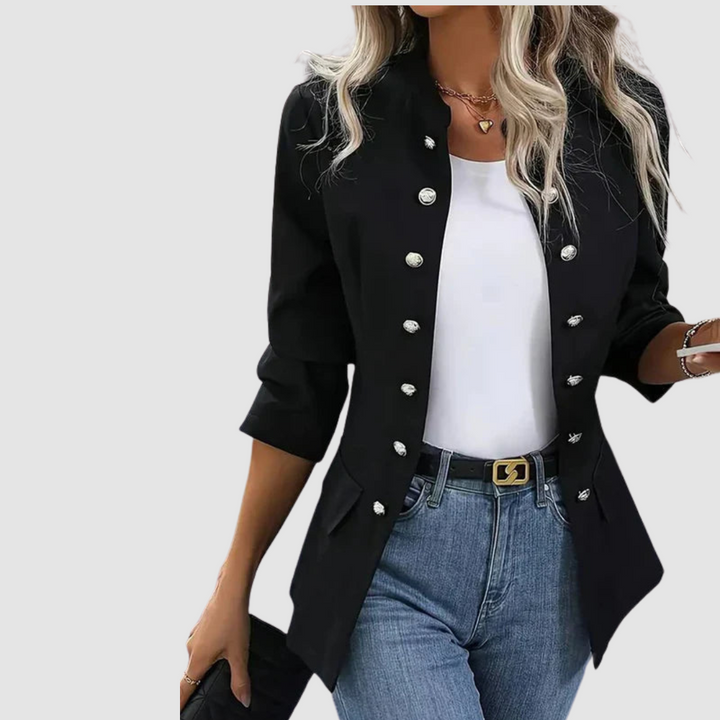 Black buttoned blazer over white top, jeans and belt, model holds phone, studio background.