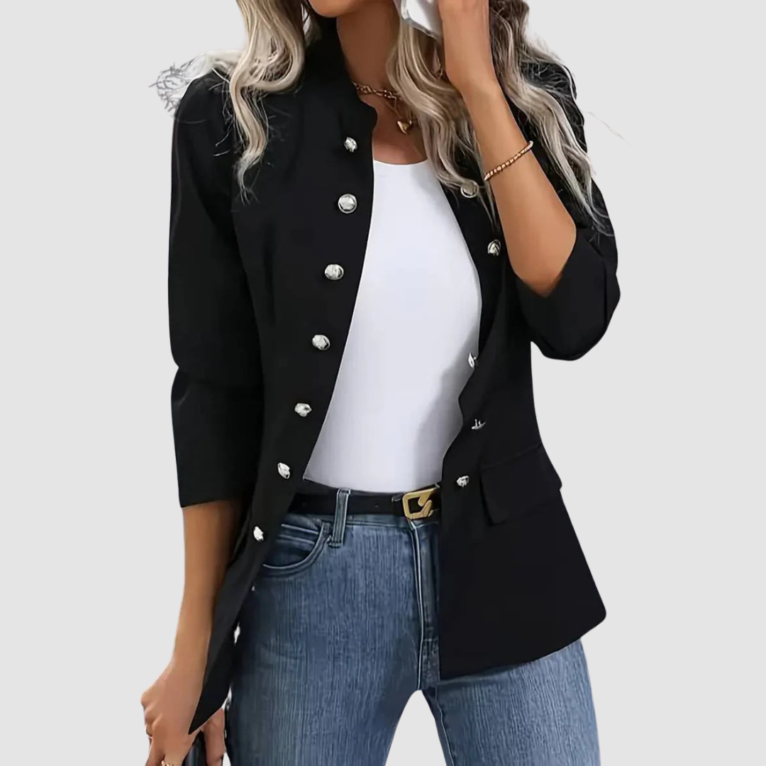 Black blazer with silver buttons, styled with white top and jeans, model holding a clutch, studio setting.