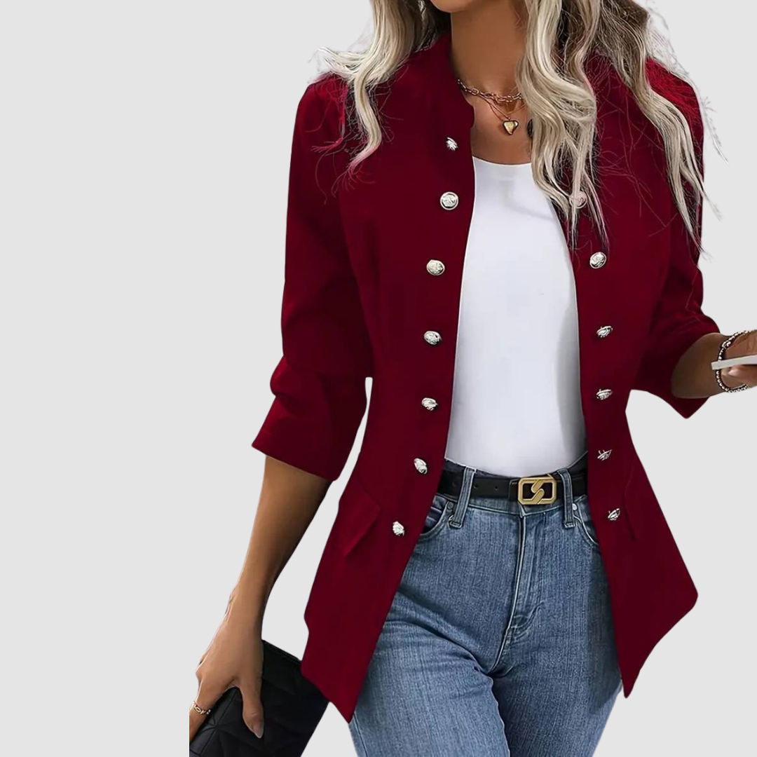 Model in burgundy blazer with button details over white top and jeans, studio backdrop.