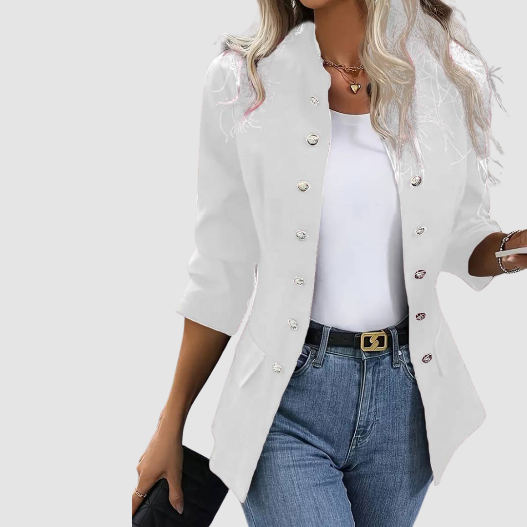White blazer with shiny buttons, worn over white top and jeans, complemented with black belt, studio setting.