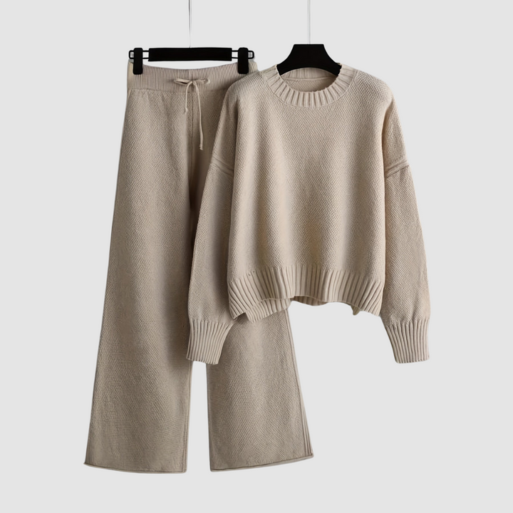 Beige knit loungewear set with a relaxed sweater and wide-leg pants on hangers, white background.