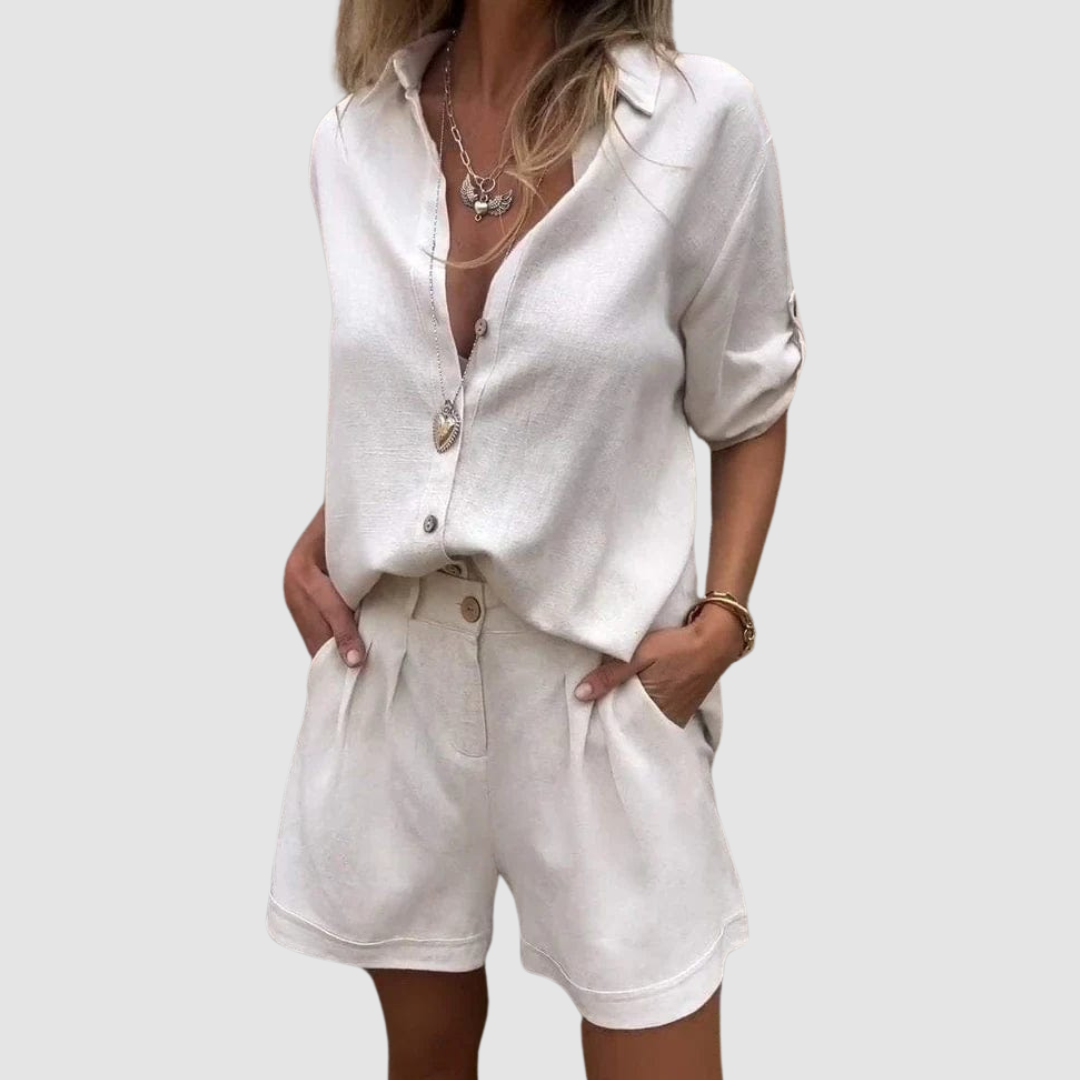 Woman in a light beige summer set featuring a button-up blouse and shorts, studio background.