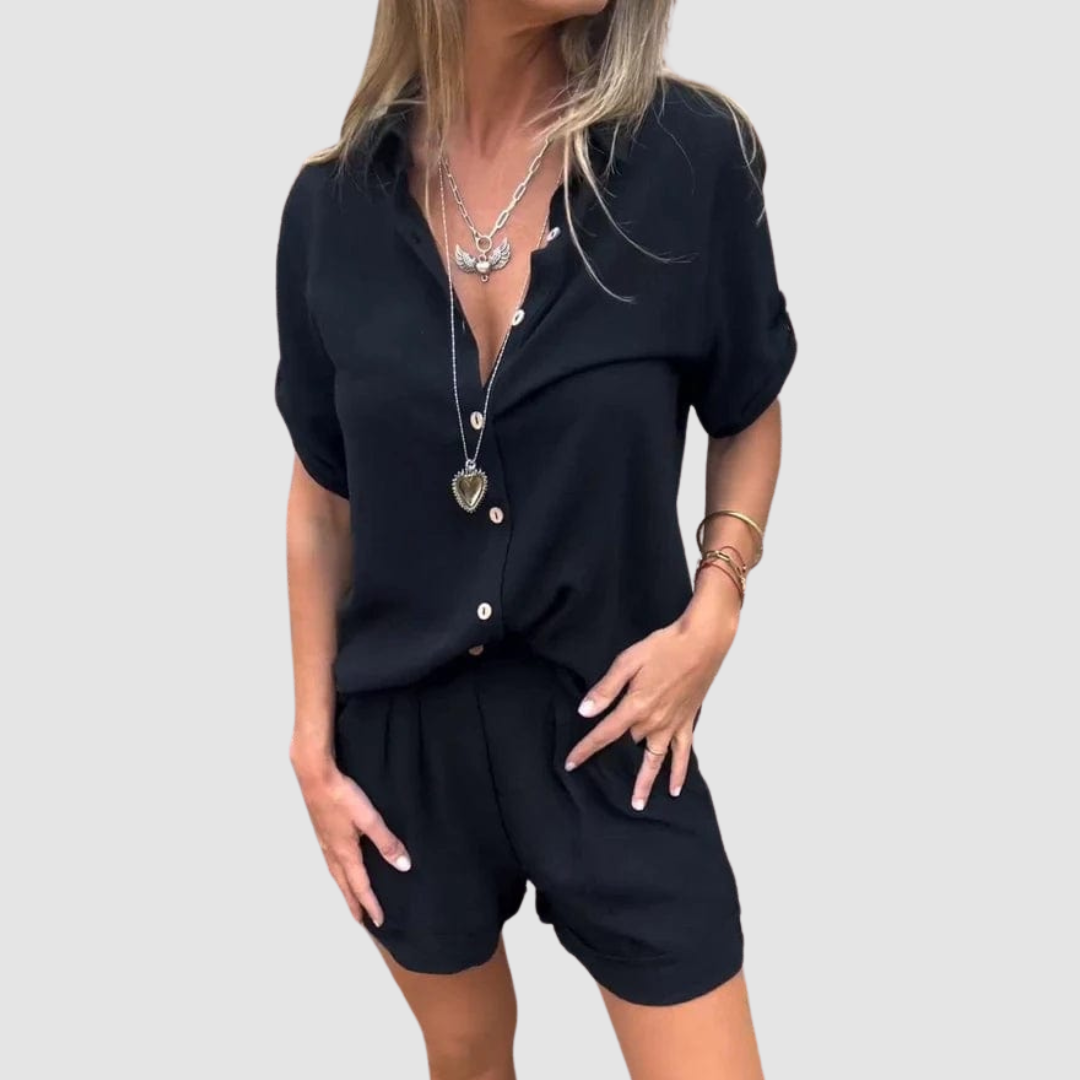 Woman dressed in a dark navy summer set with a button-up blouse and shorts, studio background.