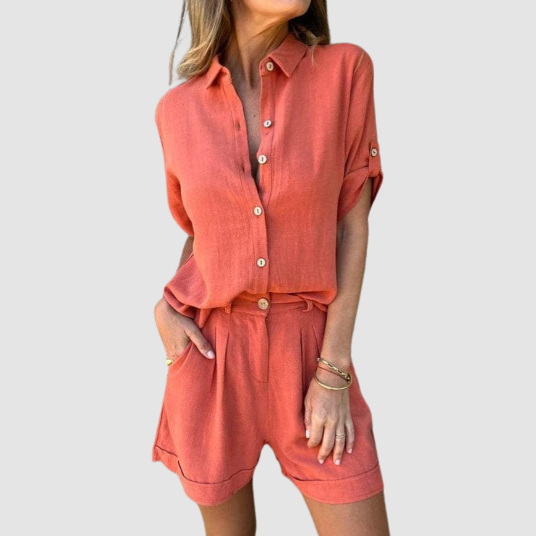 Woman wearing a bright orange summer set with button-up blouse and shorts, studio background.