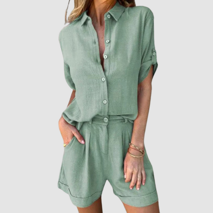 Woman in a light green summer set with button-up blouse and shorts, studio background.