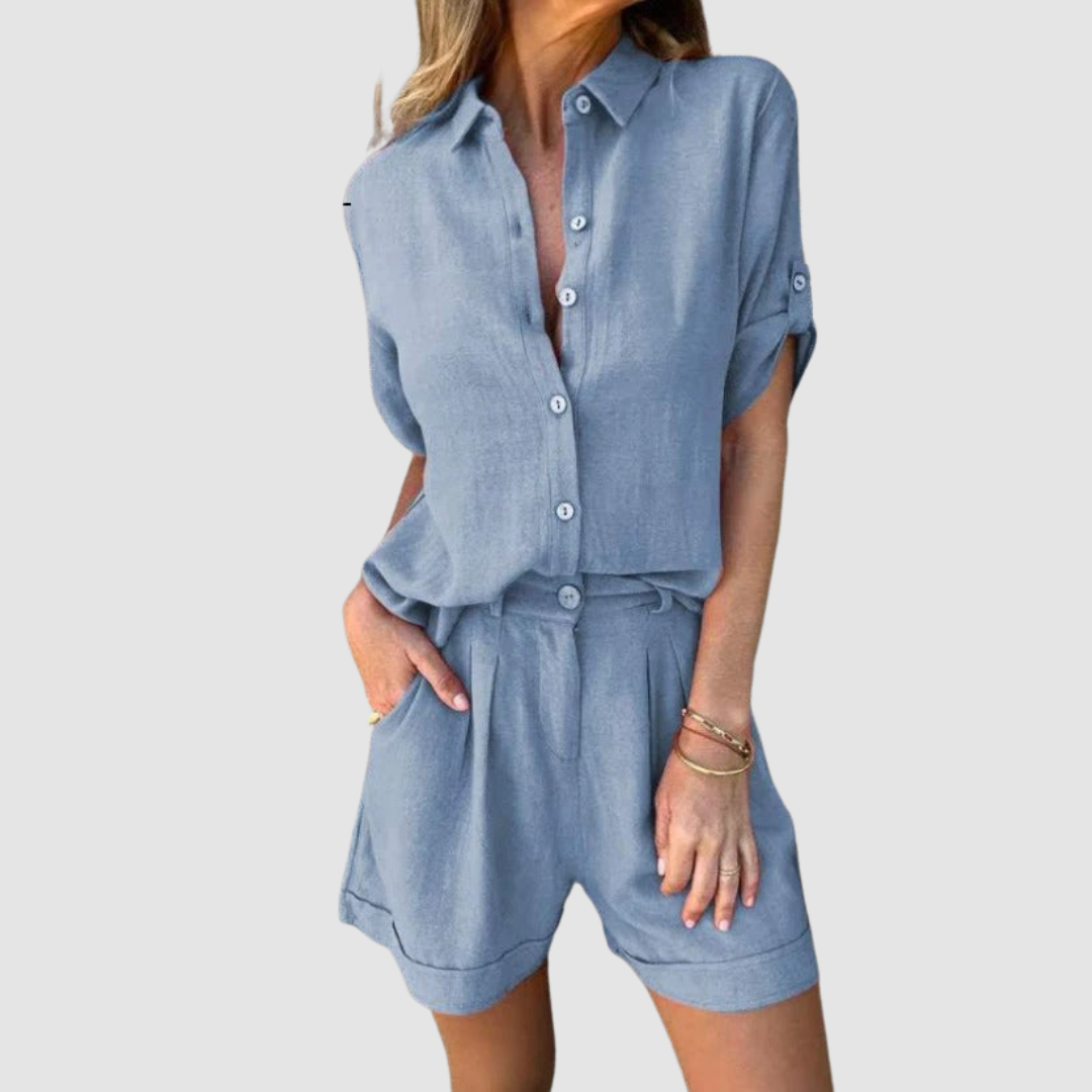 Woman in a light blue summer set with a button-up blouse and shorts, studio background.