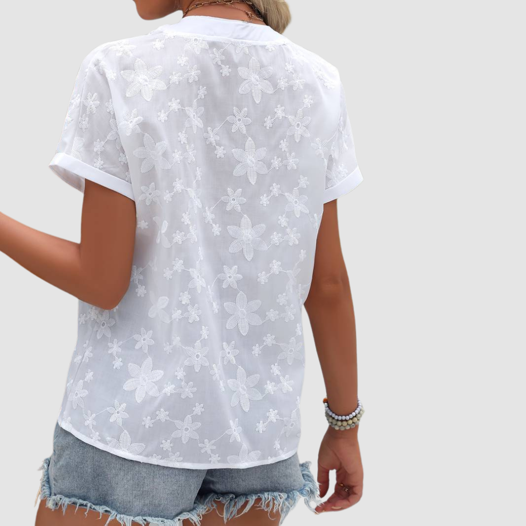 Back view of a white floral loose shirt with rolled sleeves, worn with denim shorts, studio background.