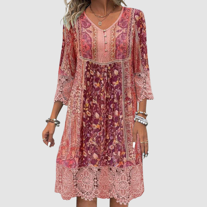Front view of boho dress in red tones with floral pattern, lace details, worn by model, plain background.