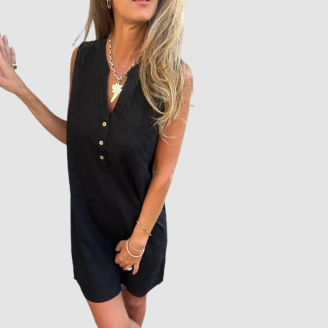Woman in a sleeveless black dress with button detail, posing casually with a hand gesture. Studio setting.