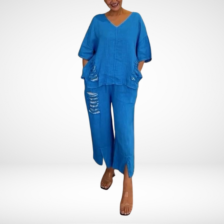 Woman in blue two-piece summer set with distressed details, standing against a white studio background.