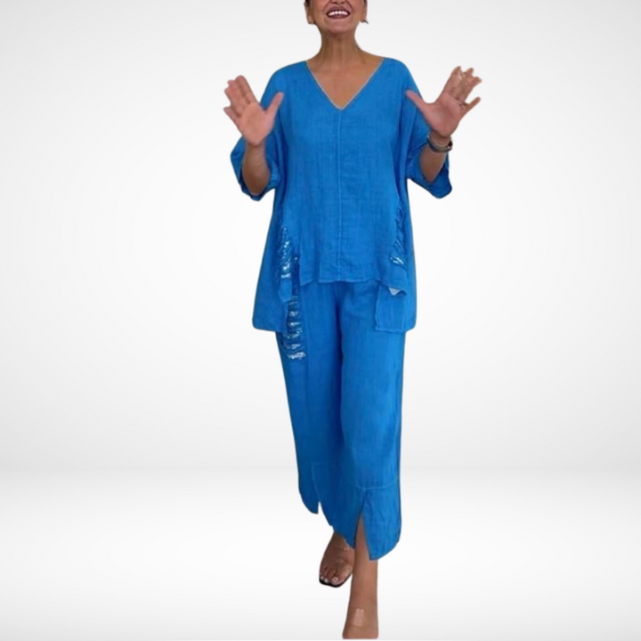 Person wearing a blue summer set, with hands raised, in a white studio environment.