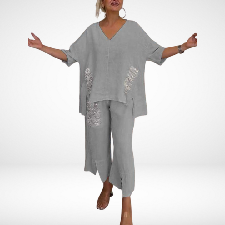 Individual modeling a gray two-piece set with subtle distressed accents in a studio setting.