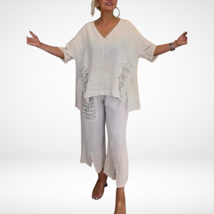 Person in white two-piece summer outfit, arms open, against a plain studio backdrop.