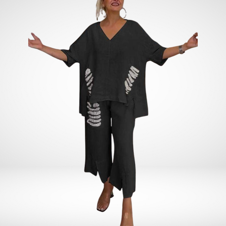 Individual in black two-piece summer set with open arms, standing in a white studio.