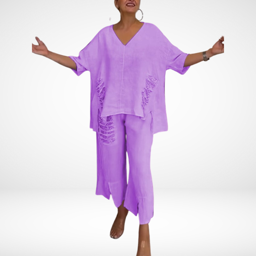 Woman in light purple two-piece summer set, arms outstretched, in a studio background.