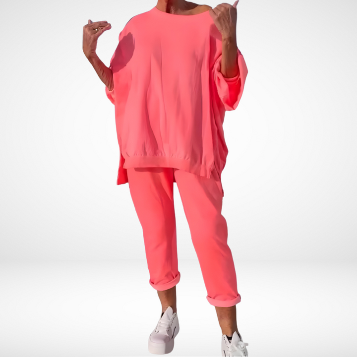 Bright pink lounge set with a relaxed fit, shown on person wearing white sneakers in a studio setting.