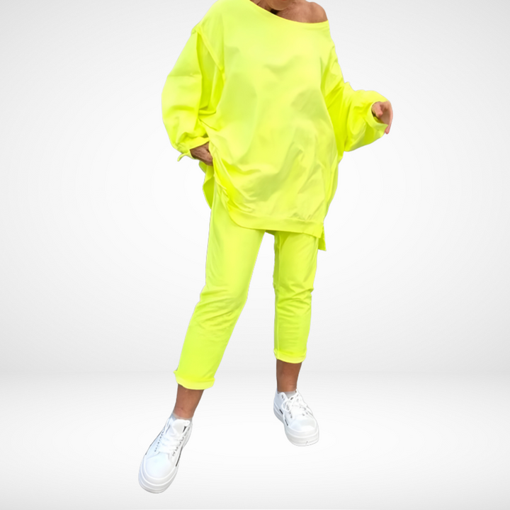 Vibrant yellow lounge set, oversized top and tapered pants, modeled with white sneakers in a bright studio.