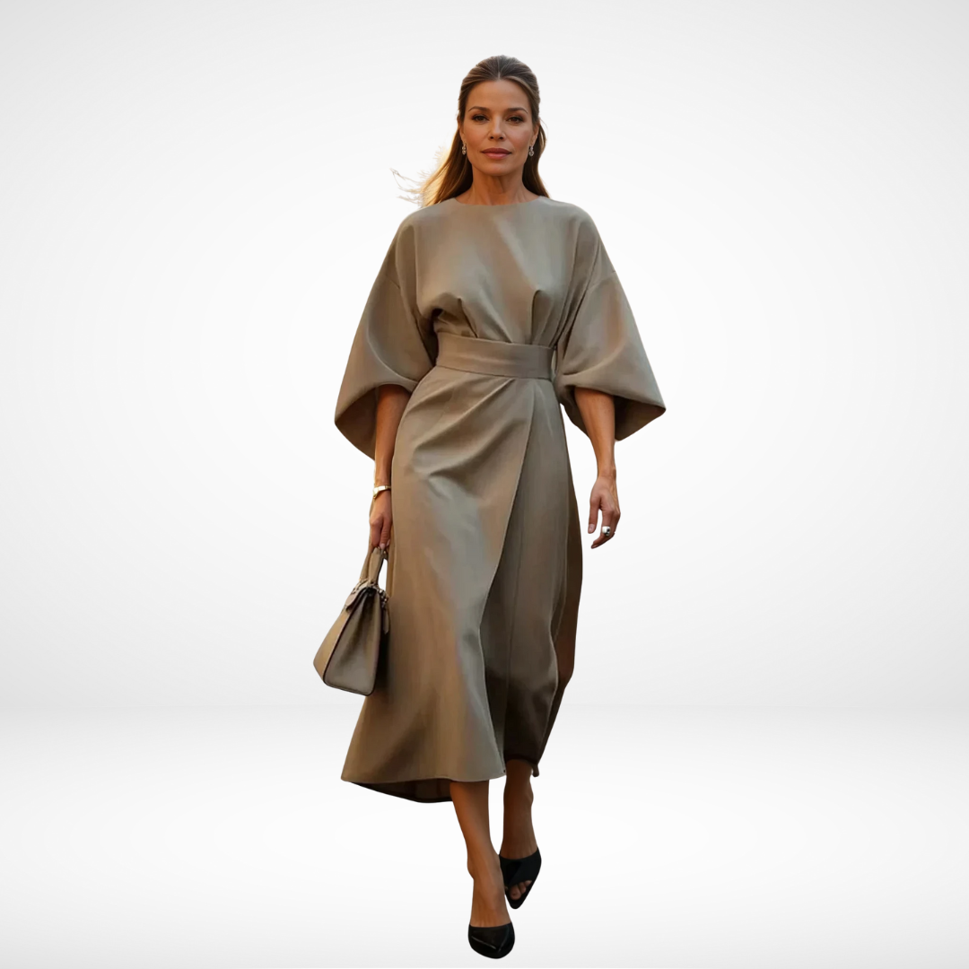 Model wearing elegant taupe midi dress with wide sleeves and waist tie, carrying a taupe handbag in a studio.