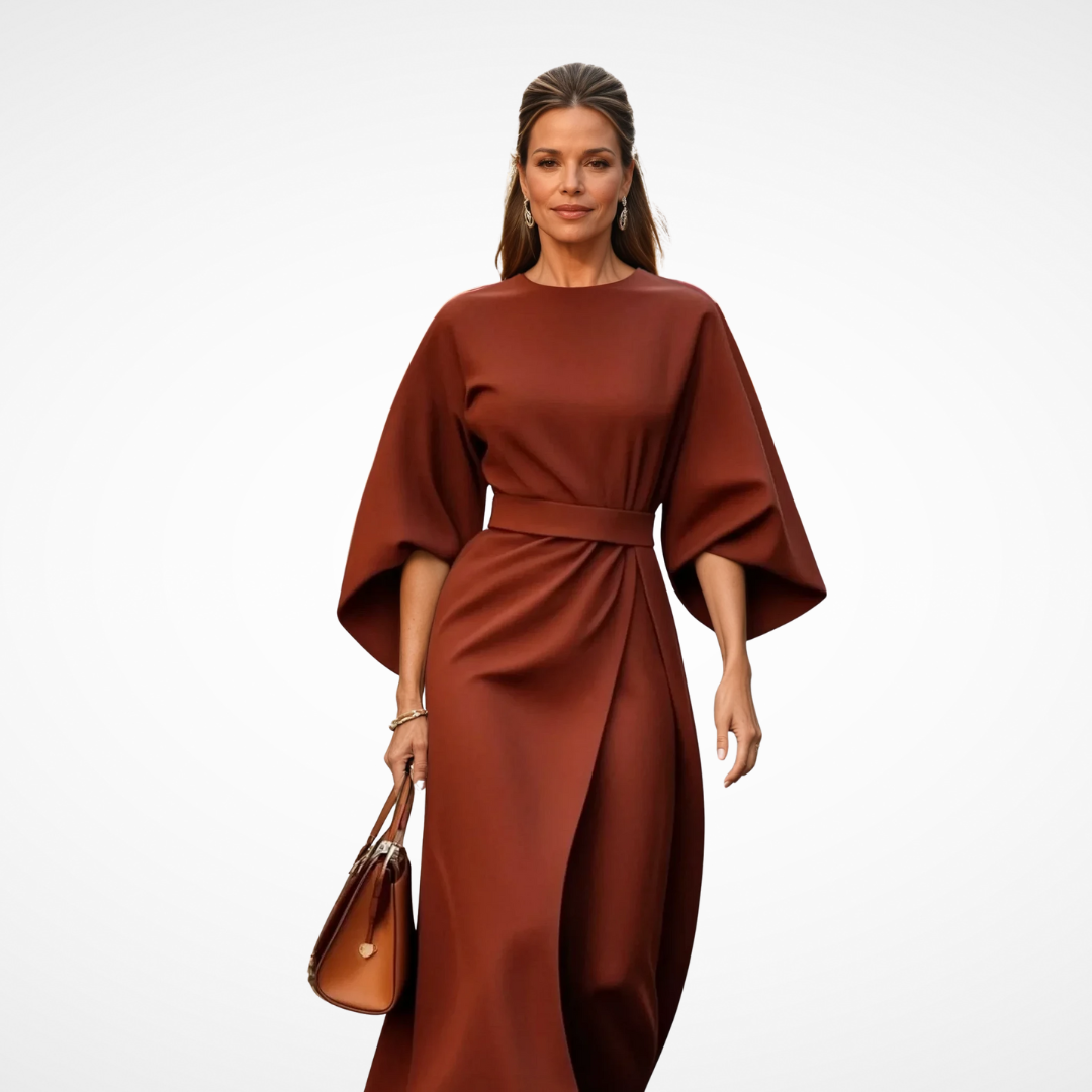 Model dressed in a sophisticated rust midi dress with wide sleeves and waist tie, holding a brown handbag in a studio.