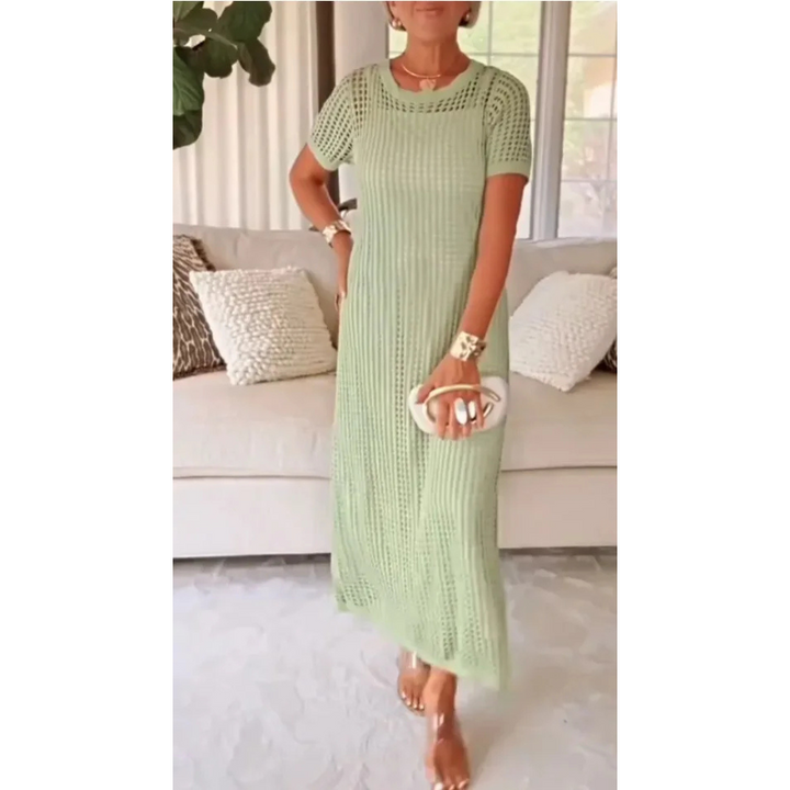 Green cut-out maxi dress worn indoors, model holding a white clutch, standing in front of a beige couch.