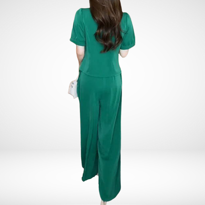 Back view of model in green short-sleeve two-piece set, in white studio setting.