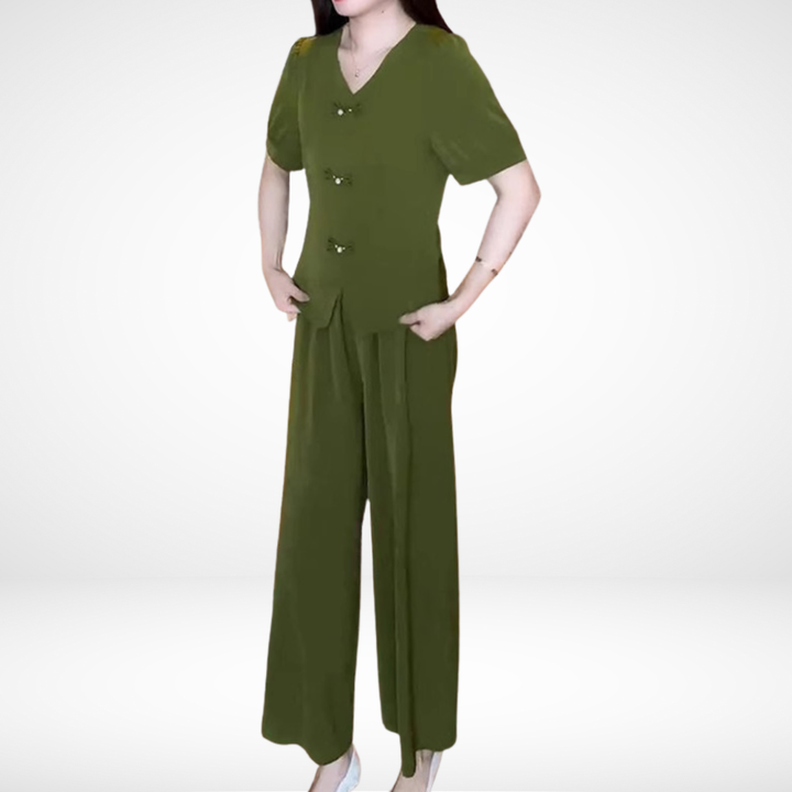 Model in olive green short-sleeve two-piece set, hands on hips, against white studio background.