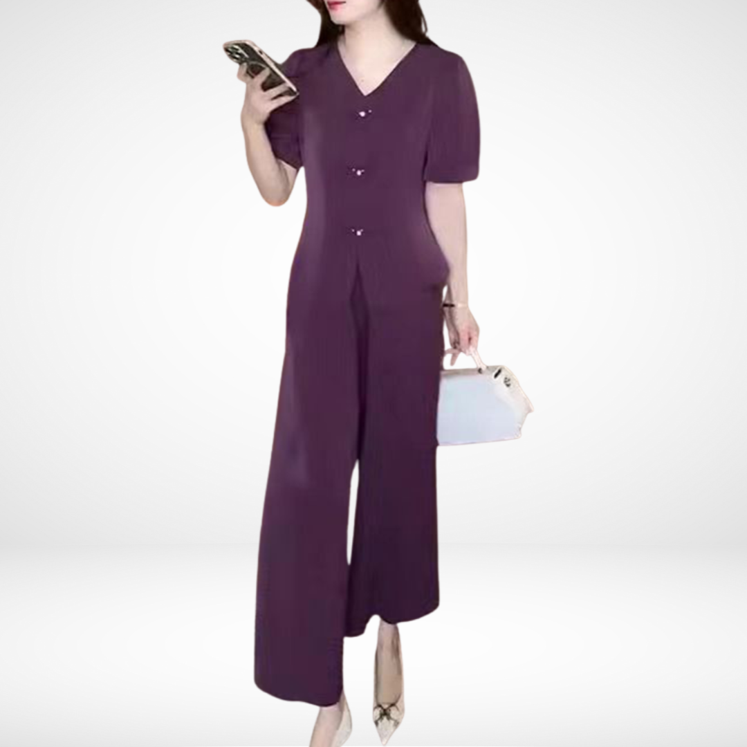 Model in purple short-sleeve two-piece set, holding phone and white bag, against white studio background.