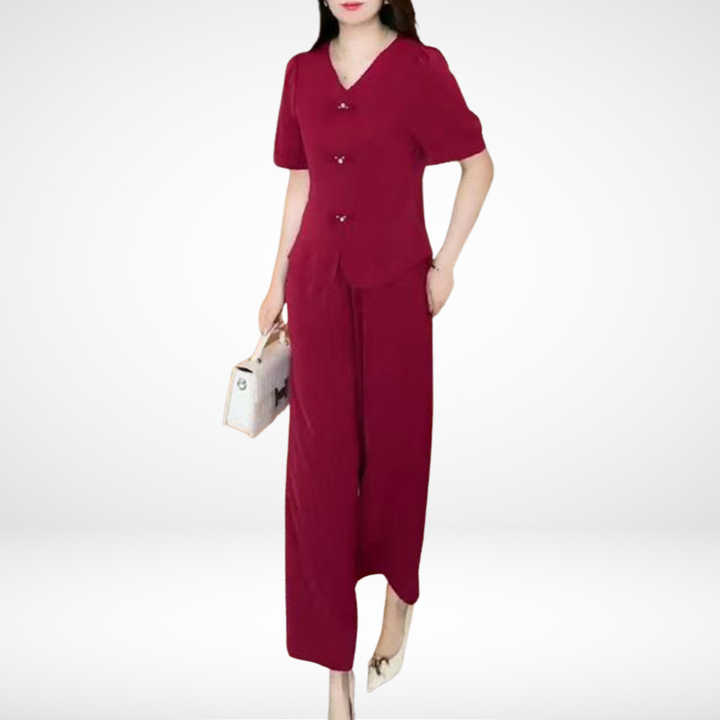 Model in red short-sleeve two-piece set, holding white bag, in white studio setting.