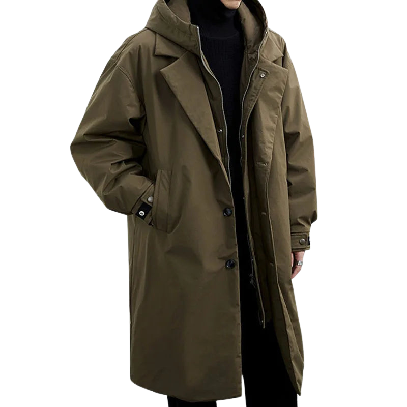 Person wearing a brown long coat with hood and buttons in a studio setting.