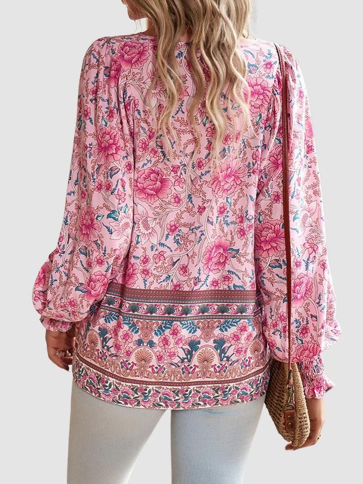 Back view of pink floral blouse with intricate patterns and denim jeans, set against a neutral studio background.