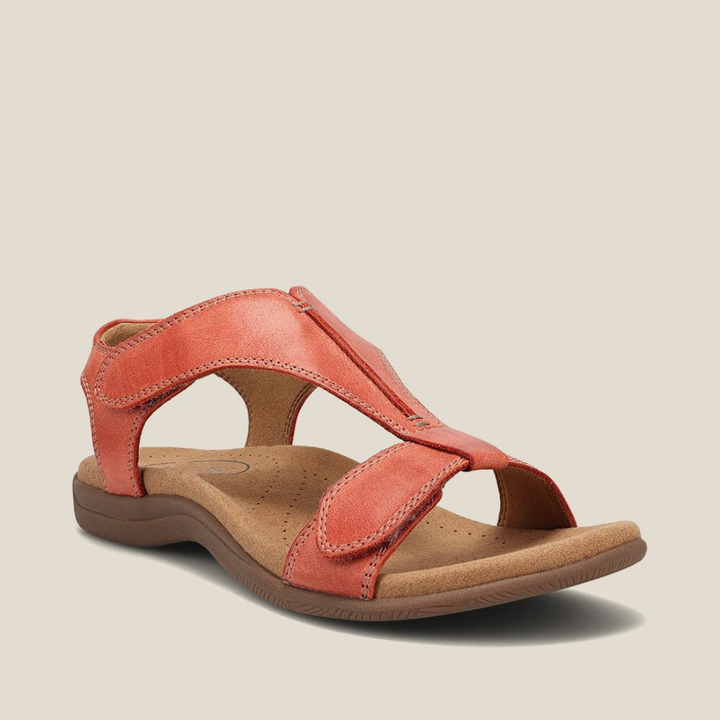 Red orthopedic sandal with supportive sole, adjustable straps, and simple design on beige background.