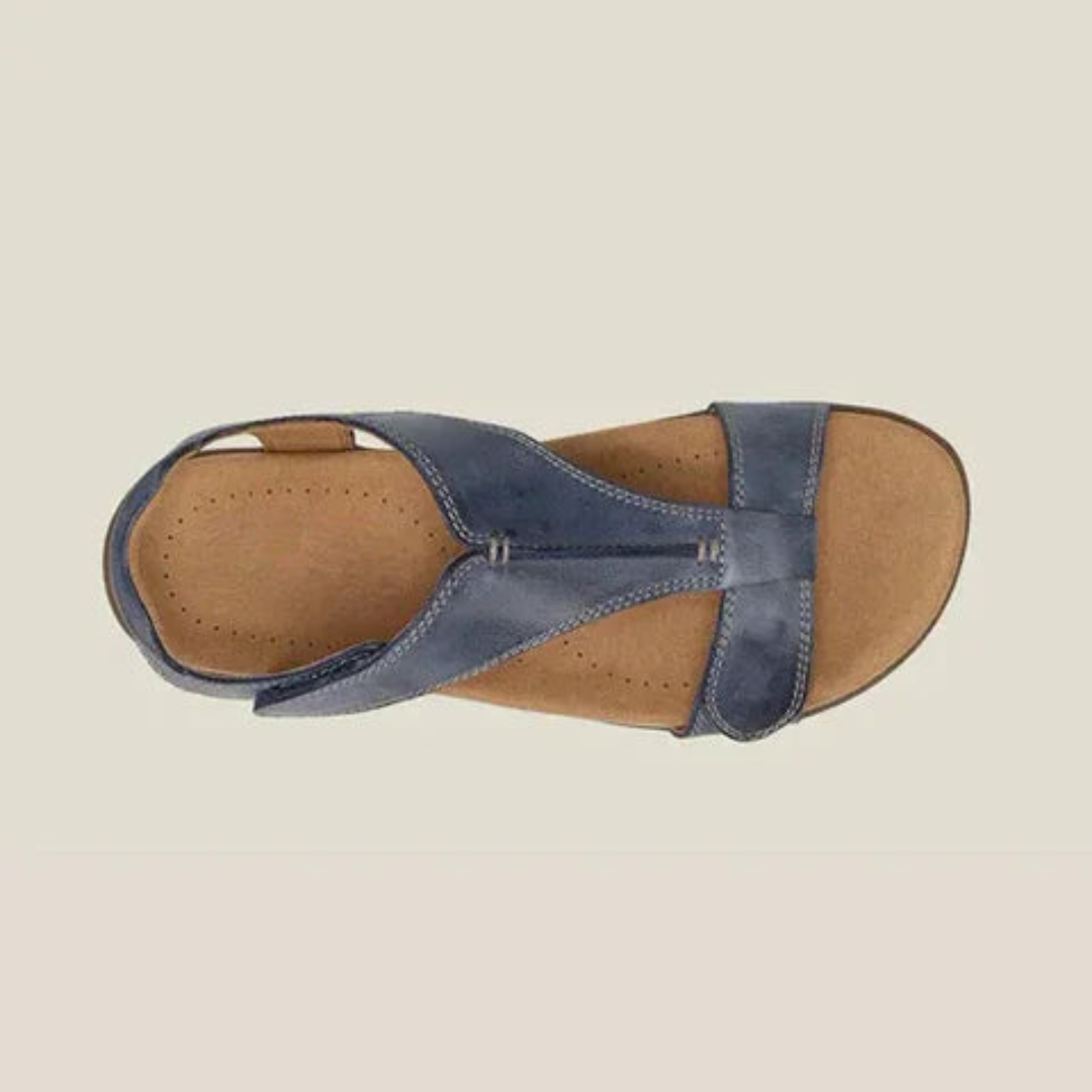 Top view of blue orthopedic sandal with contoured footbed and robust straps on beige background.