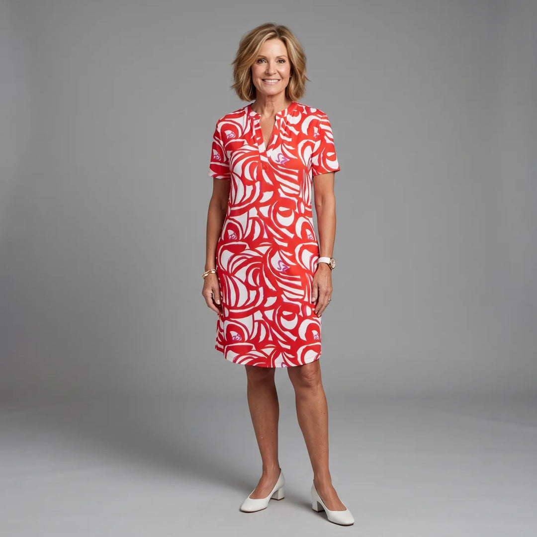 Woman wearing a red and white patterned summer dress in a studio setting, smiling.